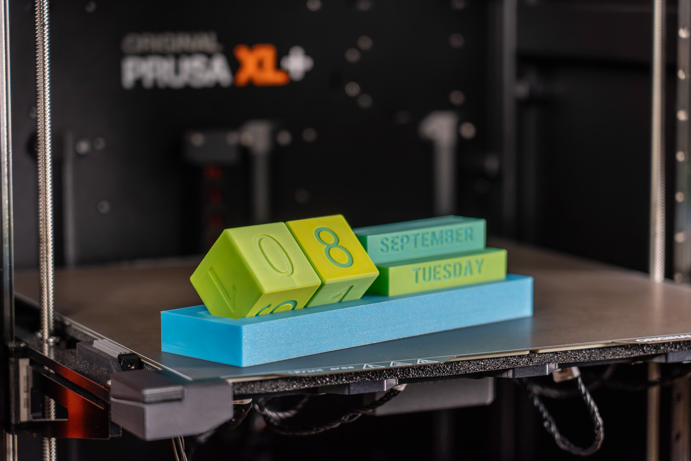 A 3D printer with a stack of blocks on its build plate.